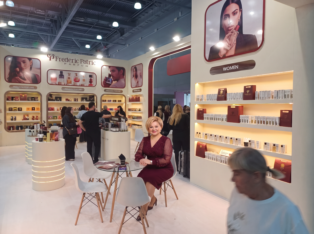 Интерьер стенда Frederic Patric Parfum: зона с продукцией WOMEN, светящиеся полки с парфюмерией, женщина в бордовом платье сидит за столиком
